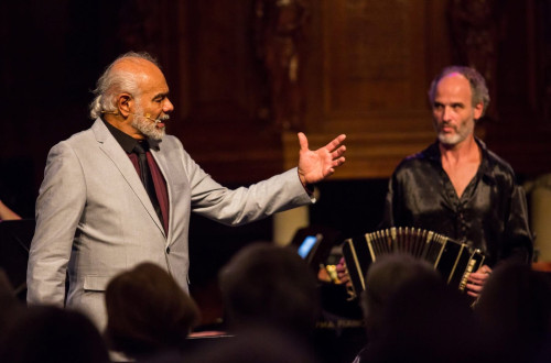 Moski poje, za njim moski igra harmoniko.