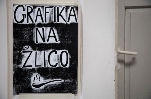 A white door, next to it a black poster displaying a spoon.