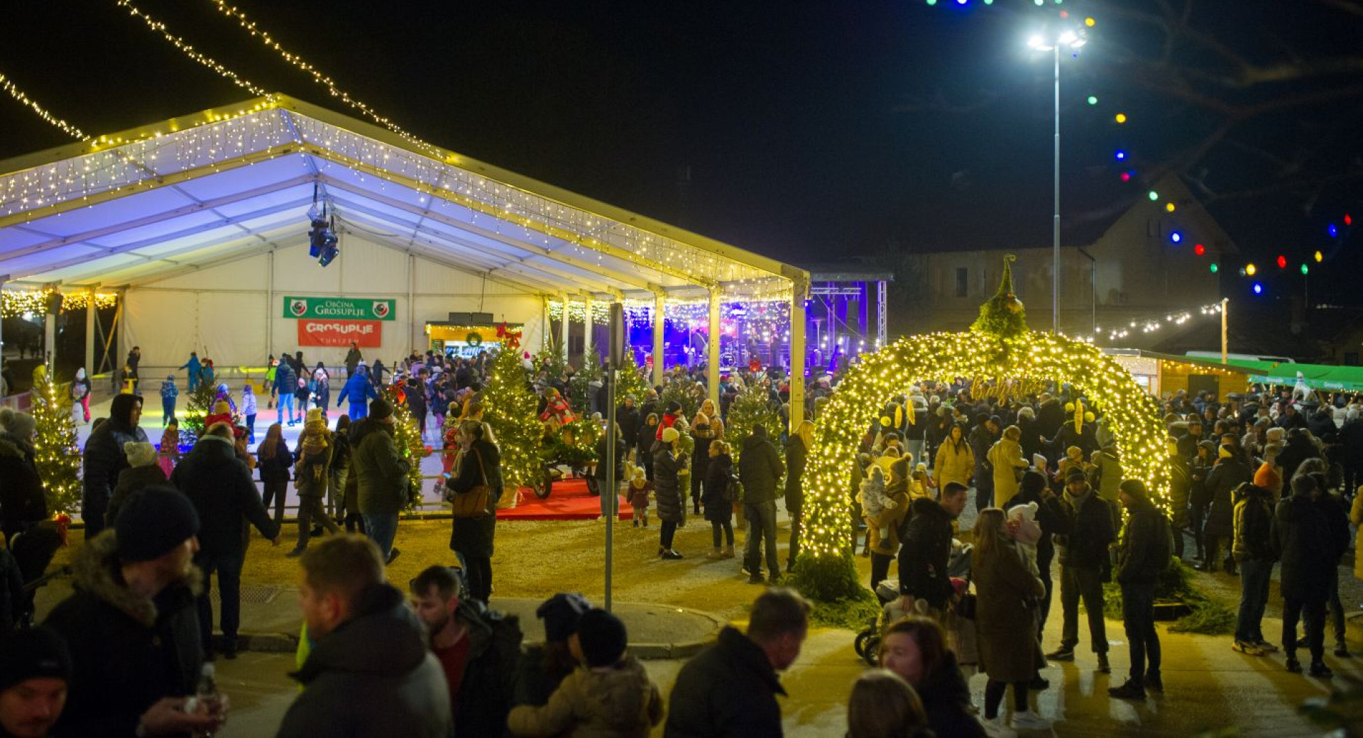 Praznicna noc na prostem, kjer se ljudje druzijo ob praznicni osvetlitvi.