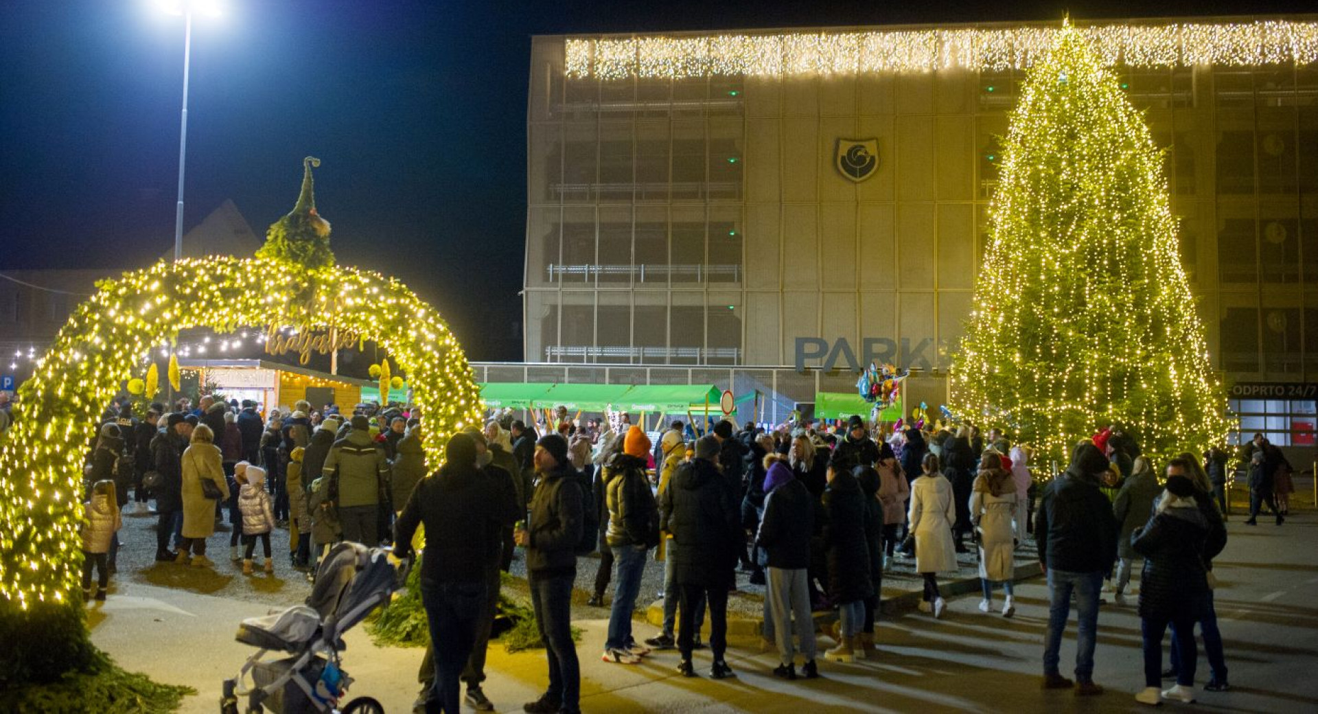 Gruca ljudi je zunaj v objemu praznicne osvetlitve.