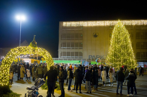 Gruca ljudi je zunaj v objemu praznicne osvetlitve.