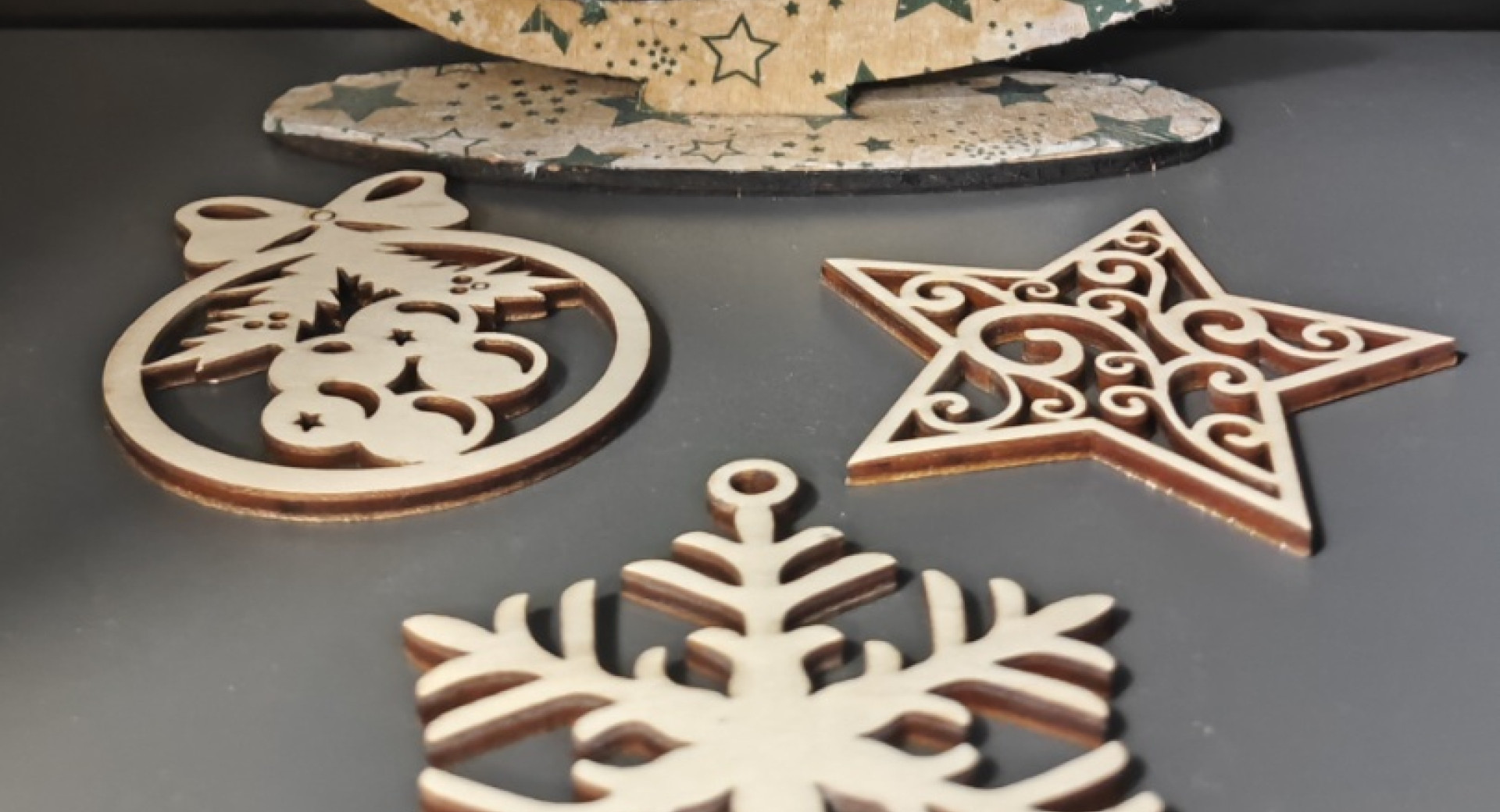 Leseni novoletni okraski razstavljeni na sivi mizi.