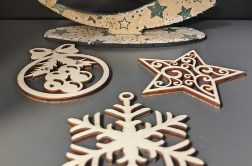 Leseni novoletni okraski razstavljeni na sivi mizi.