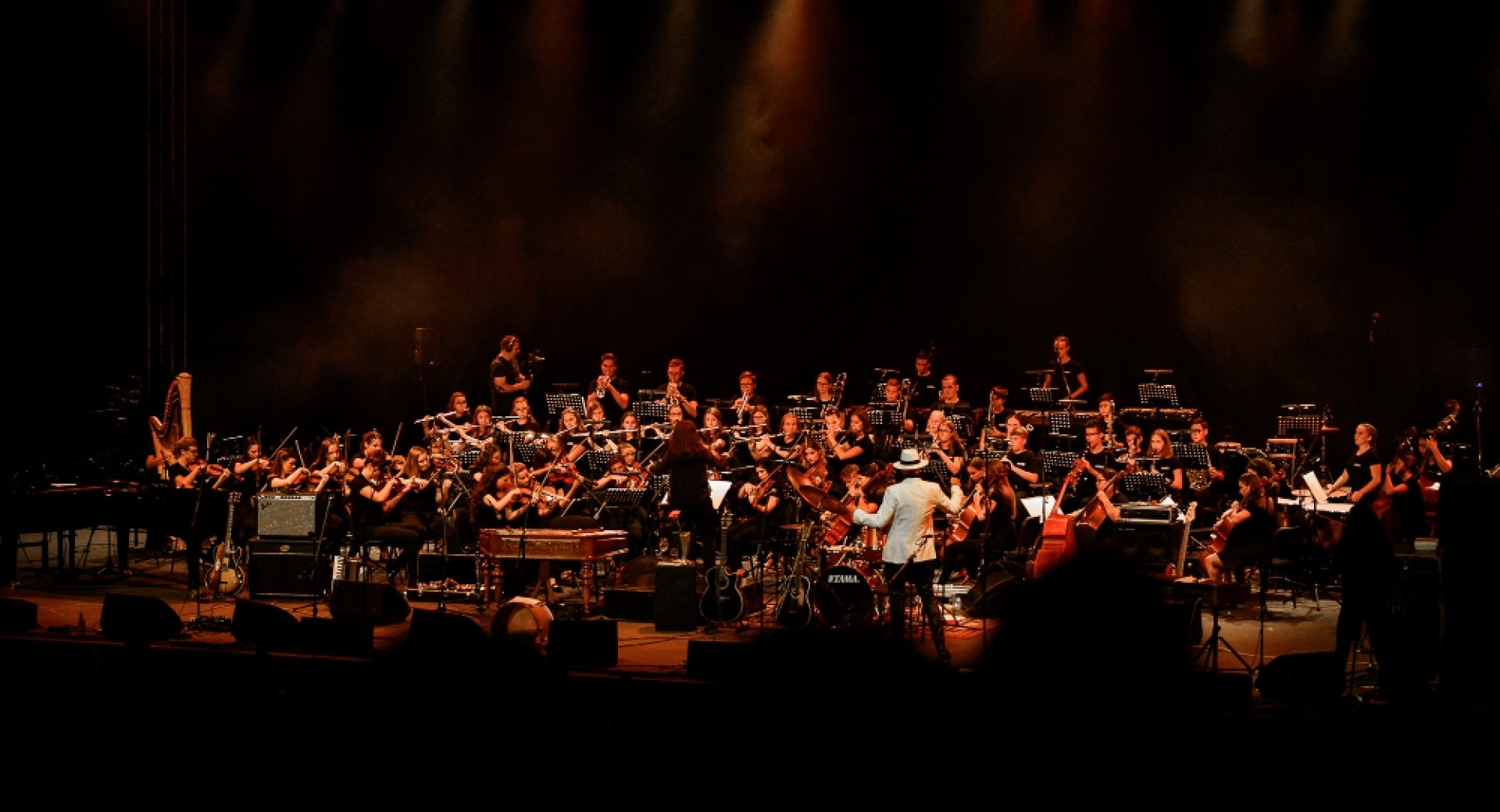 An orchestra on stage, bathed in red light against the darkness.