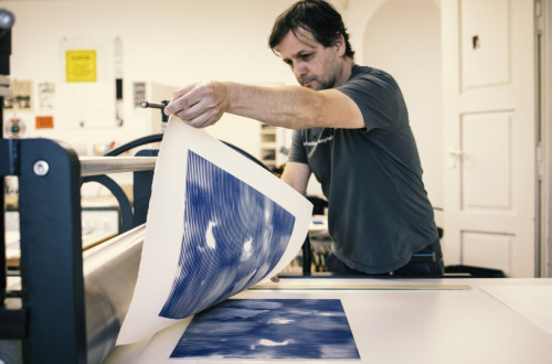 Moski s pomocjo velikega stroja tiska umetnino na velik papir.