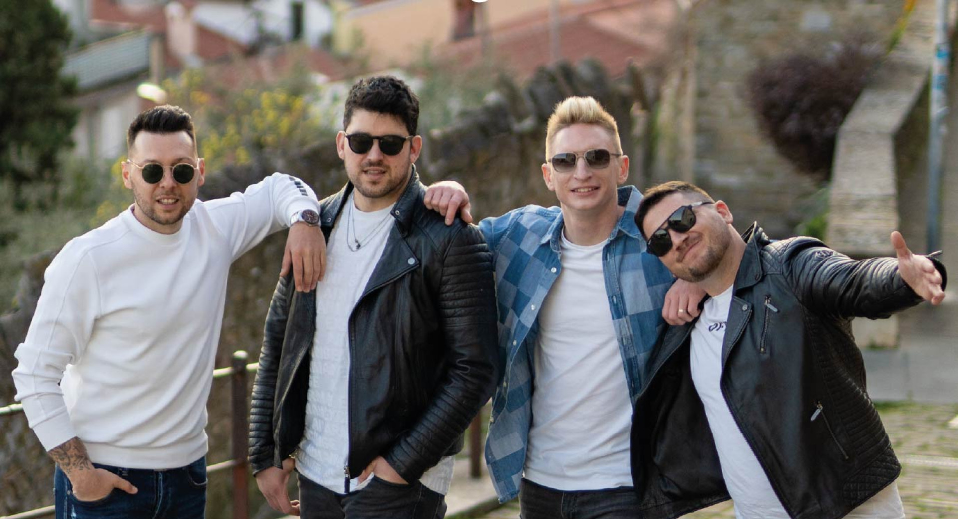 Stirje mladi moski pozirajo za fotografijo na prostem in nosijo crna soncna ocala.