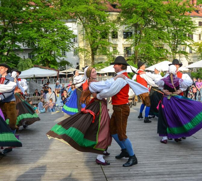Skupina plesalcev v tradicionalnih ljudskih oblacilih na nabrezjih.