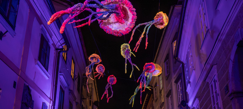 Art installations in the shape of jellyfish above the city at night.