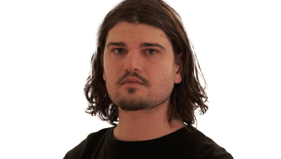 Portretna fotografija moskega z daljsimi rjavimi lasmi.