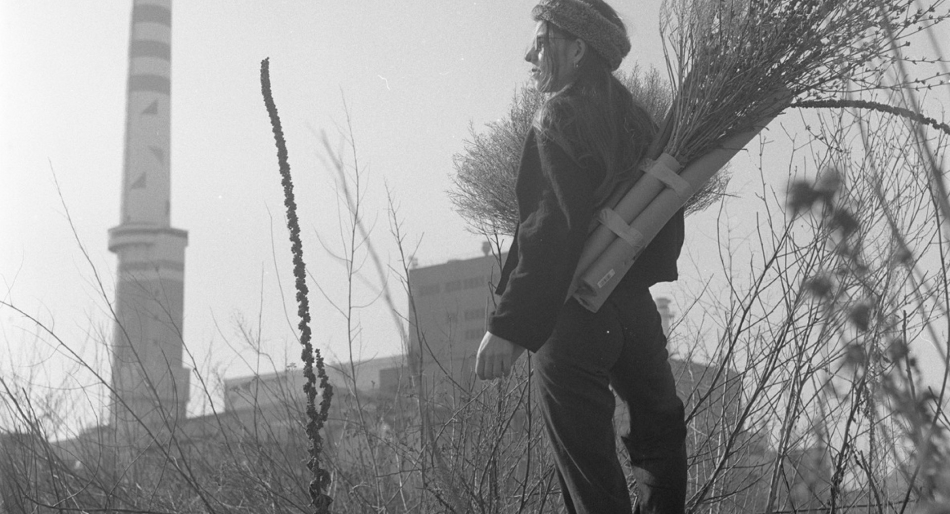 Crnobela fotografija zenske na vrhu hriba, ki zre na mesto.