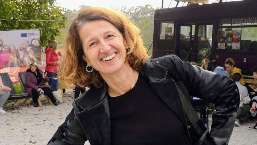 Zenska z rjavimi lasmi v crnih zgornjih oblacilih in kavbojkah.