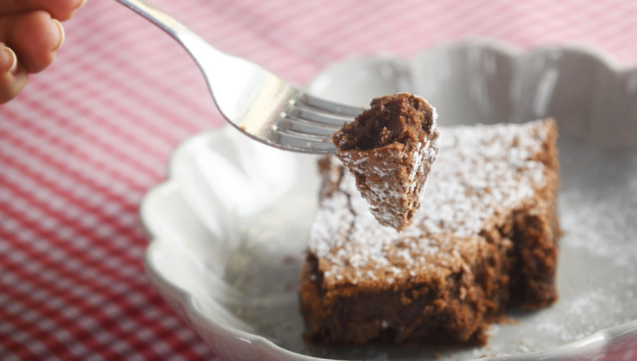 Temen biskvit, posut z belim prahom na vilici nad kroznikom. 