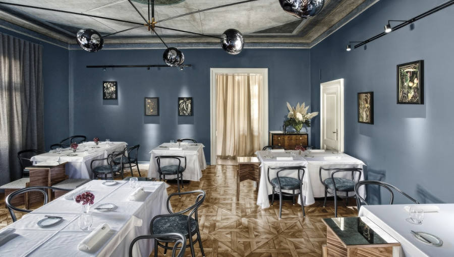 Velika soba z modrimi stenami in pogrnjenimi mizami. 