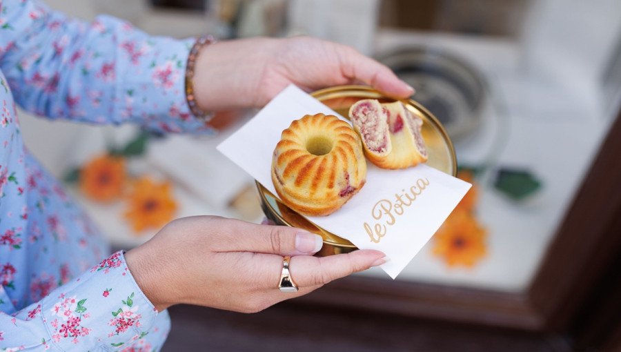 Majhna malinova poticka in na pol prerezana poticka na prticku v zenskih rokah.