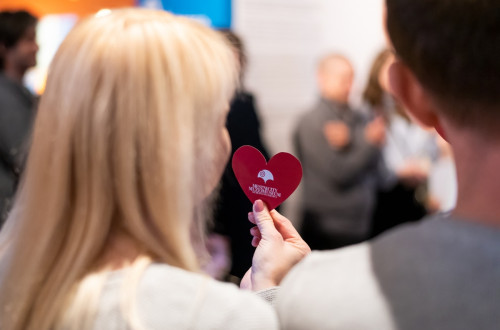 Moski in zenska, ki v rokah drzi majhen rdec srcek, fotografirana od zadaj.