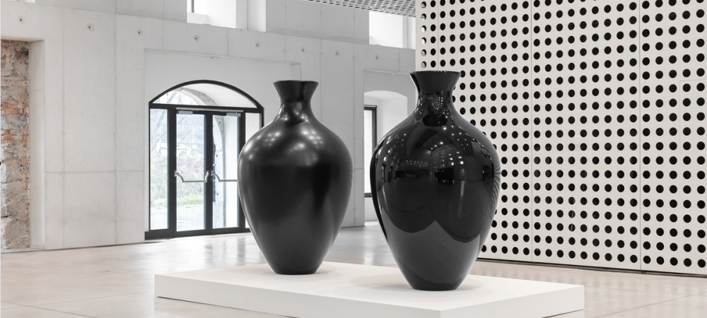Dve ogromni crni vazi sredi bele sobe.