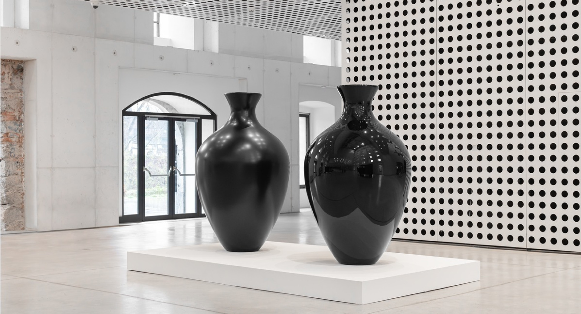 Dve ogromni crni vazi sredi bele sobe.