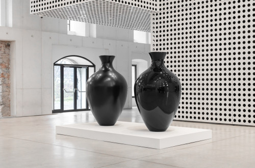 Dve ogromni crni vazi sredi bele sobe.