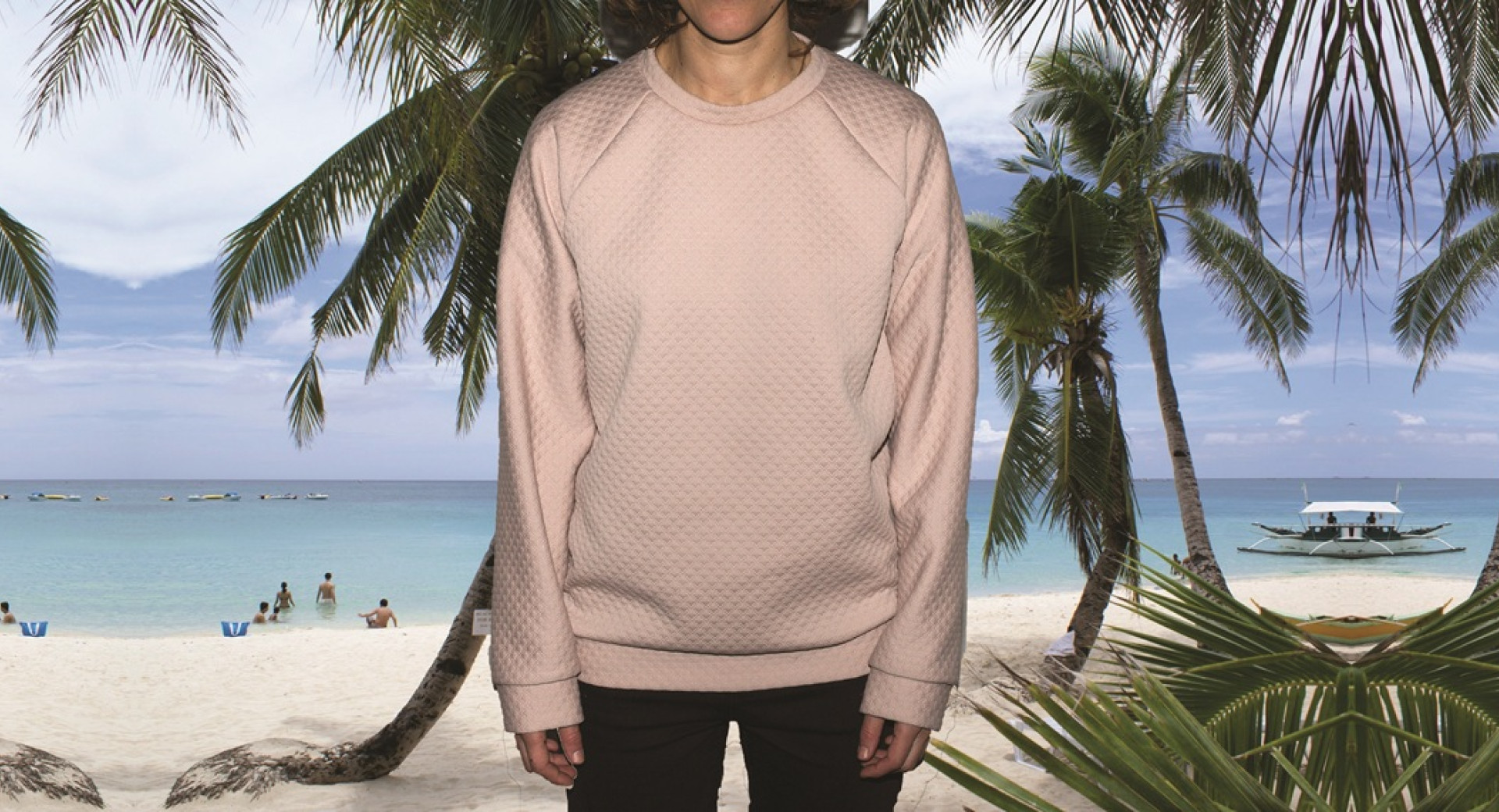 Moski v bez puloverju pred plazo z mivko, palmami in morjem. 