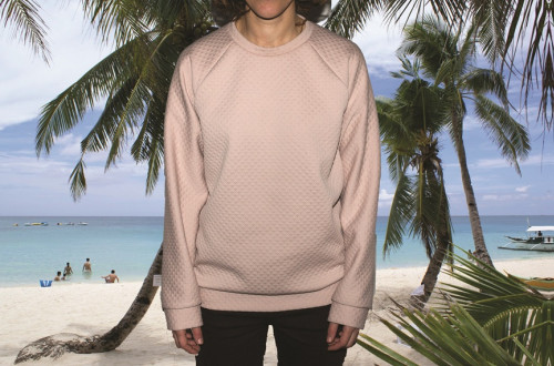 Moski v bez puloverju pred plazo z mivko, palmami in morjem. 