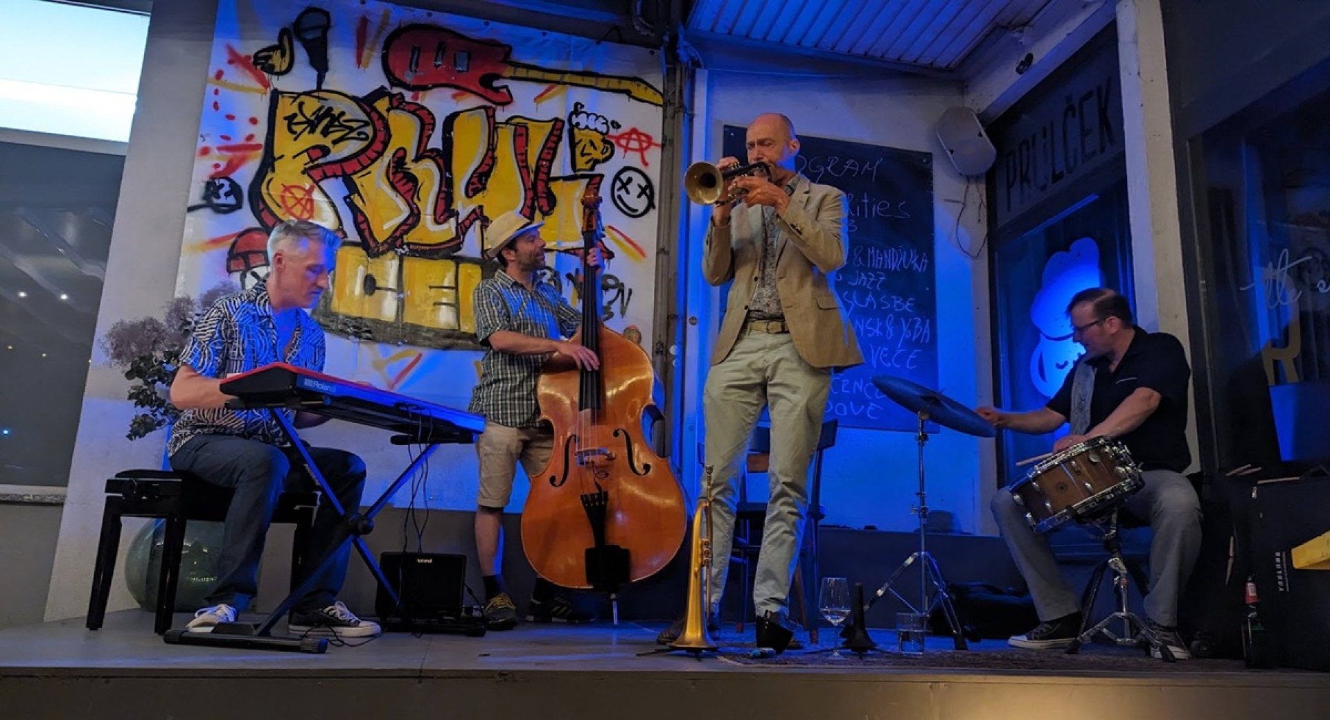 Jazz musicians on a stage with the graffiti in the background.