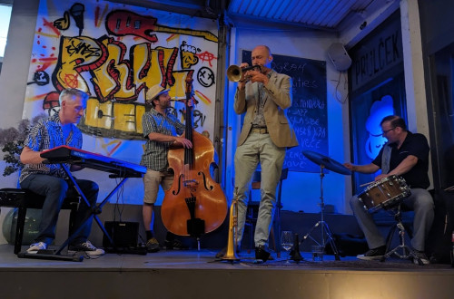 Jazz musicians on a stage with the graffiti in the background.