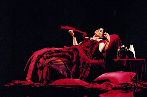 Zenska v temno rdeci obleki na odru. 