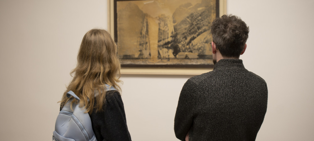 Man and woman looking at a painting on the wall.