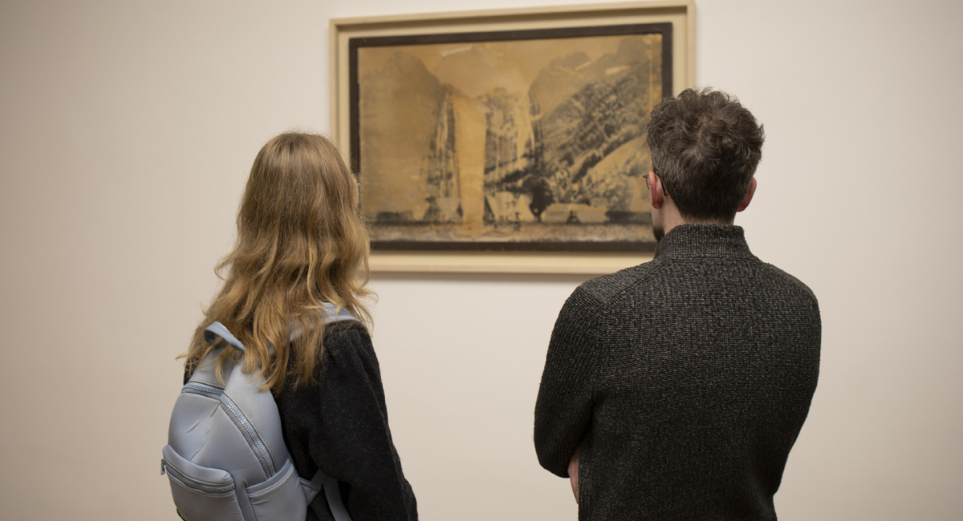 Moski in zenska si ogledujeta fotografijo na steni.