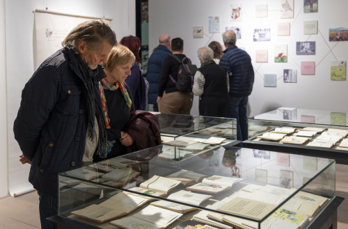 Skupina obiskovalcev si ogleduje razstavo.