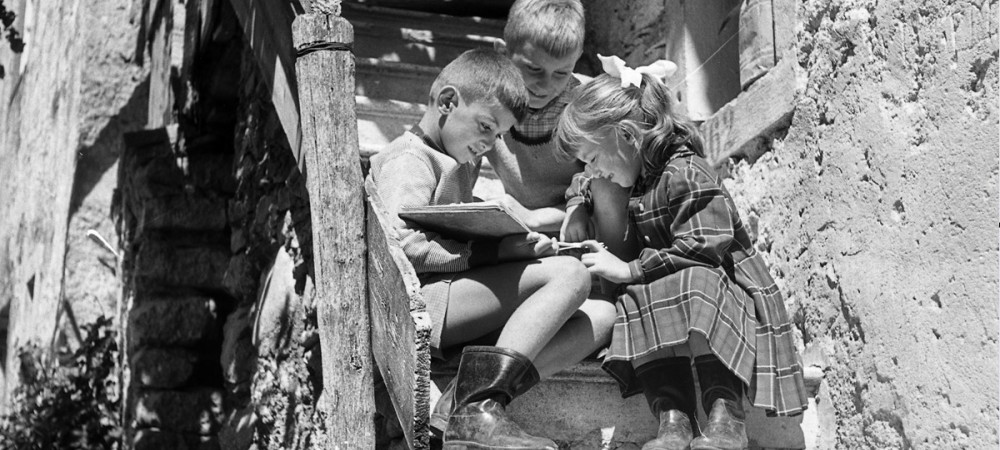 Crnobela fotografija otrok, ki sedijo na stopnicah.