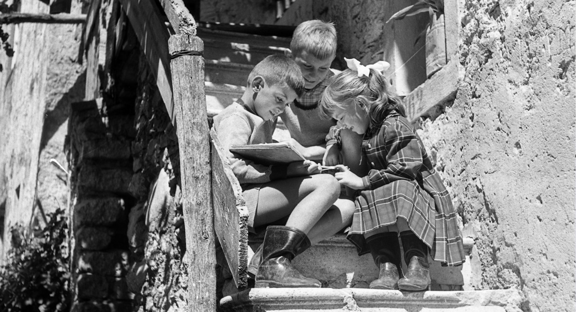 Crnobela fotografija otrok, ki sedijo na stopnicah.