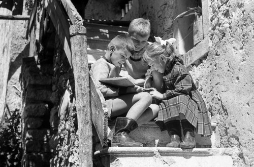 Crnobela fotografija otrok, ki sedijo na stopnicah.