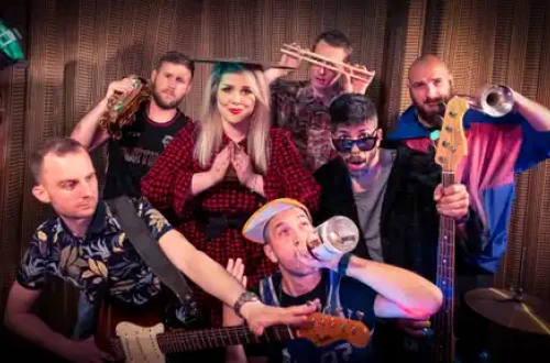 7-clanski bend pred leseno steno.