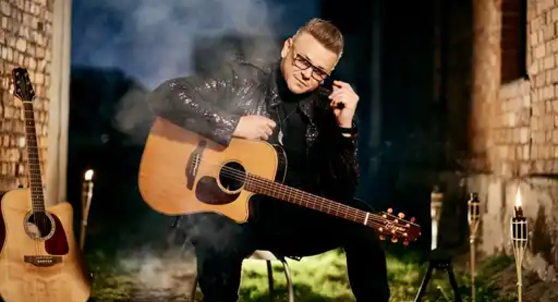 Moski s kitaro sedi na stolu med grajskimi zidovi.