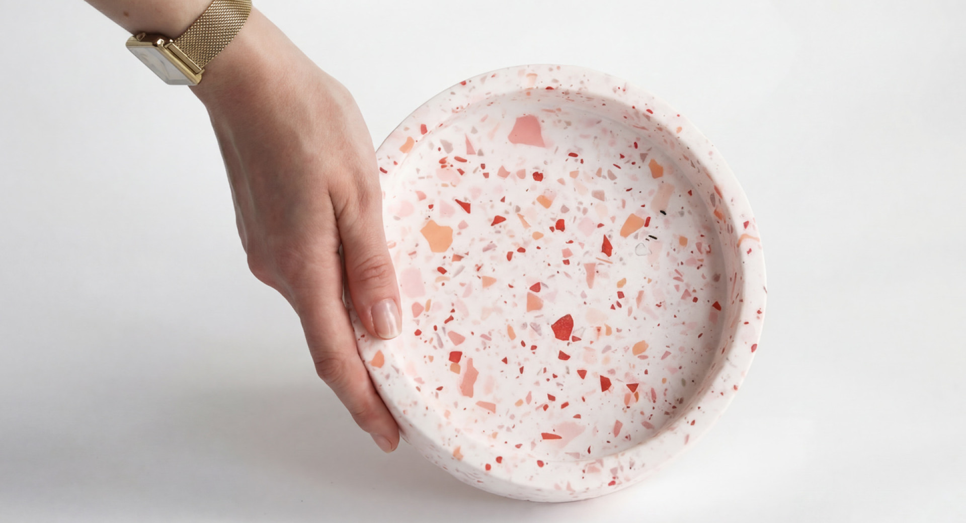 Roka z zlato uro drži krožnik narejen iz teraca.