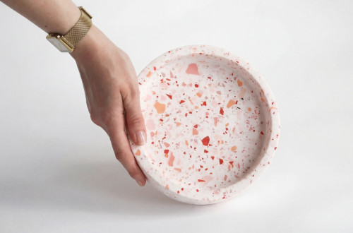 Roka z zlato uro drži krožnik narejen iz teraca.