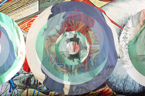 Kompleksen abstrakten kolaž s koncentričnimi krogi, ki plastijo različne slike.