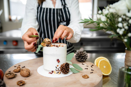 Krasenje visoke bele torte na mizi.