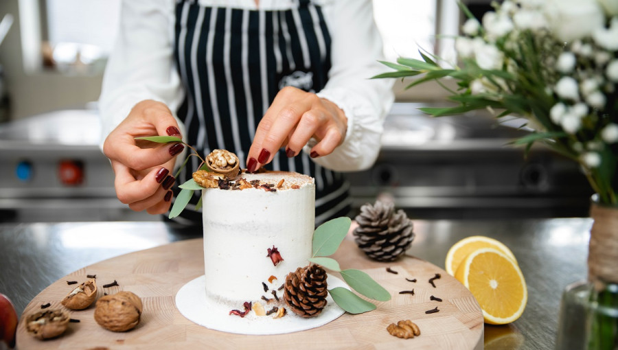 Decorating a tall white cake on a table.