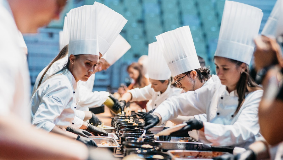 Chefs in white plating food.