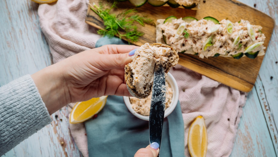 A woman spreading pate on a piece of bread.