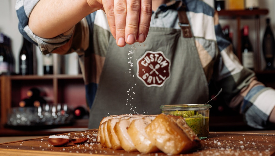 A man putting salt on a steak.