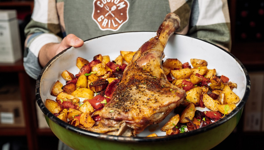 A baked lamb leg in a green dish.