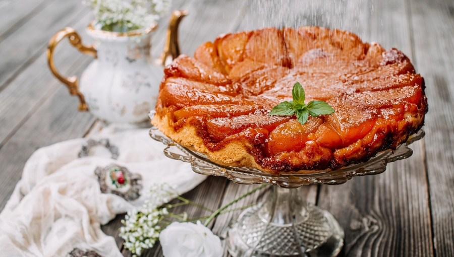 A pie with apple slices on a glass stand.