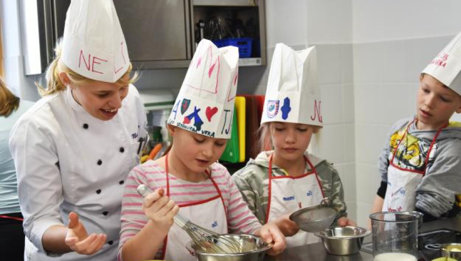 Three children cooking with a chef.