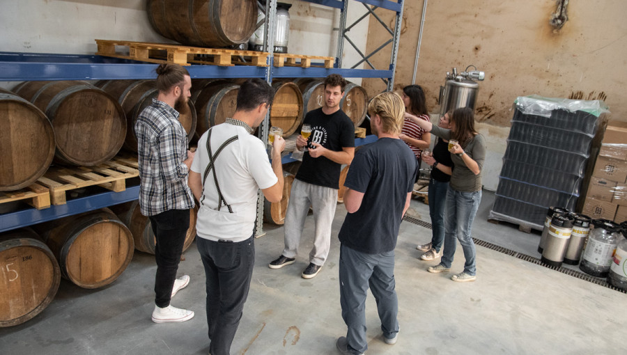 A group of people listening to a guide in a brewery.