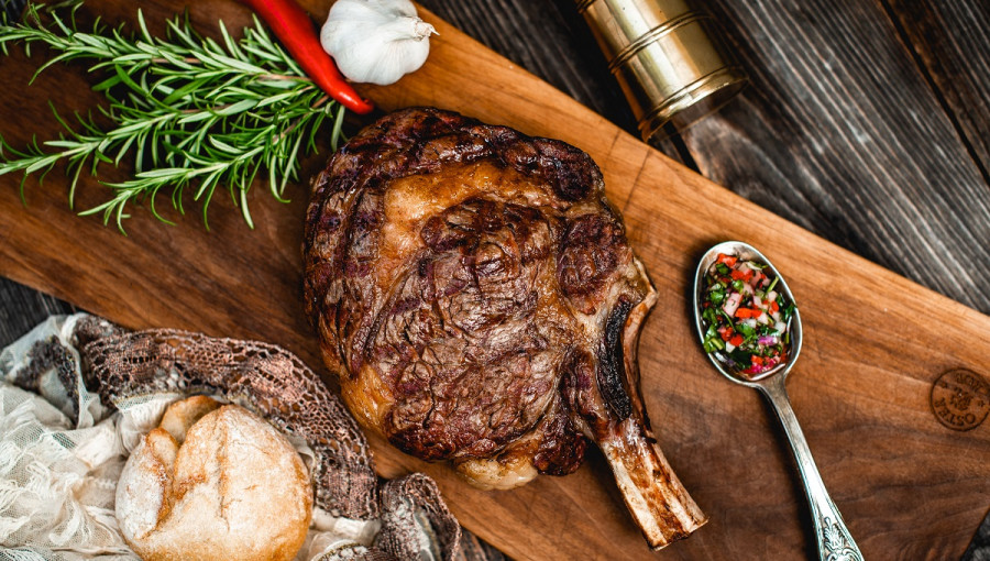 Baked steak on a platter next to a spoon with cut vegetables.