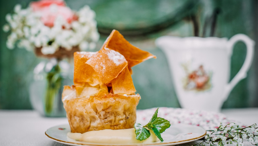 A piece of pie on a table next to a cup.
