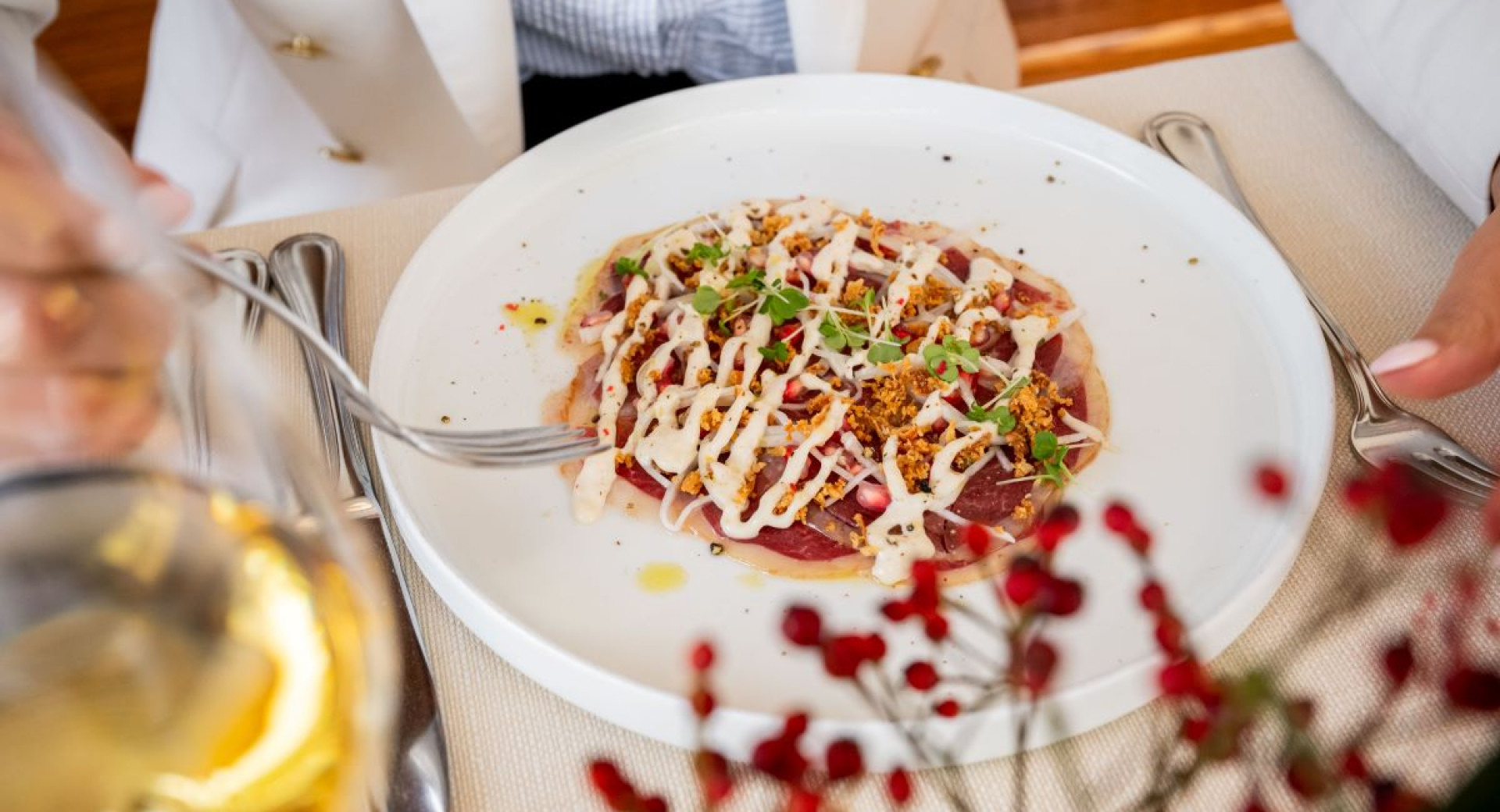 A plate features a dish in a white sauce garnished with decorative greens and crumble.